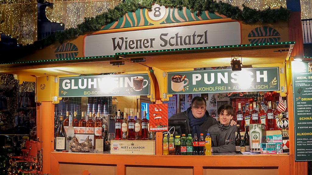 Weihnachtsmarkt-Hütte mit Verkäufer*innen hinter dem Tresen
