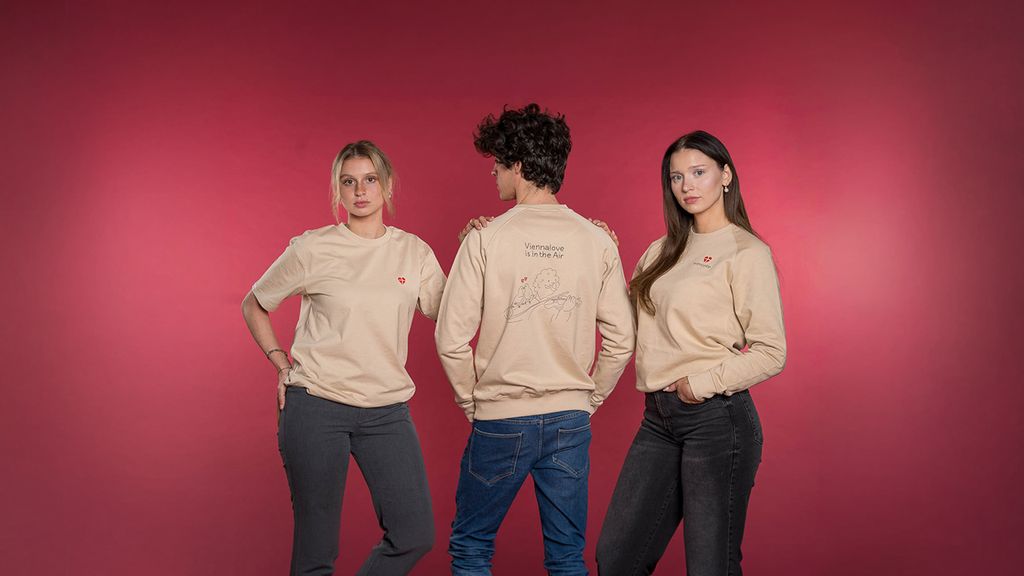 Drei Personen in beigen Sweatshirts von wienliebe vor pinkem Hintergrund