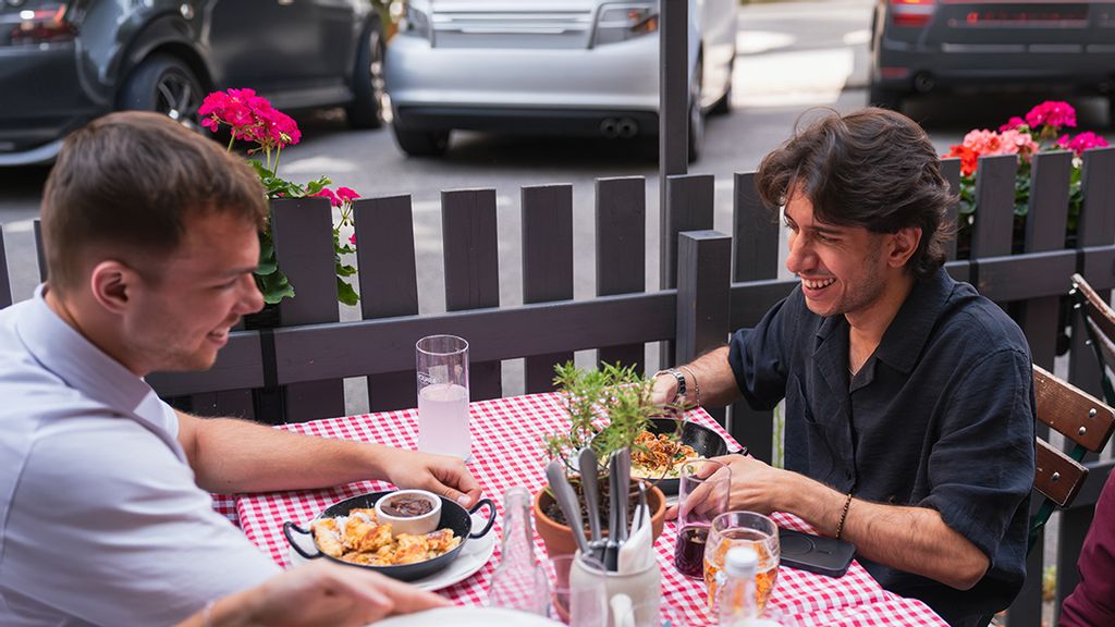 Zwei junge Männer bei einem Essen in einem Gastgarten