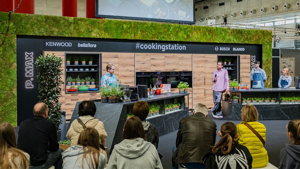 Besucher*innen der WOHNEN & INTERIEUR 2026 vor einem grün umrandeten Messestand