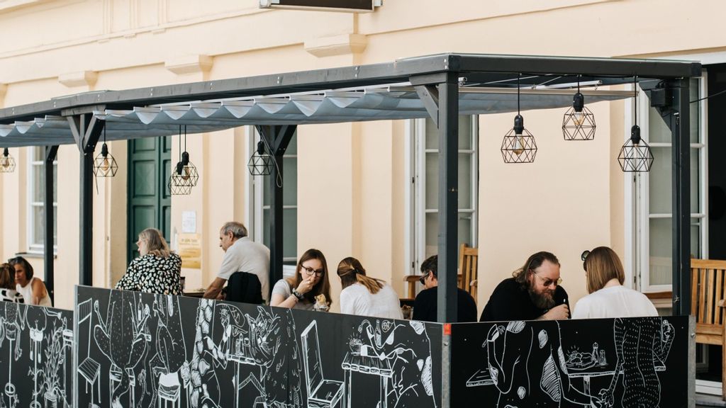 Mehrere Personen beim Essen in einem Gastgarten