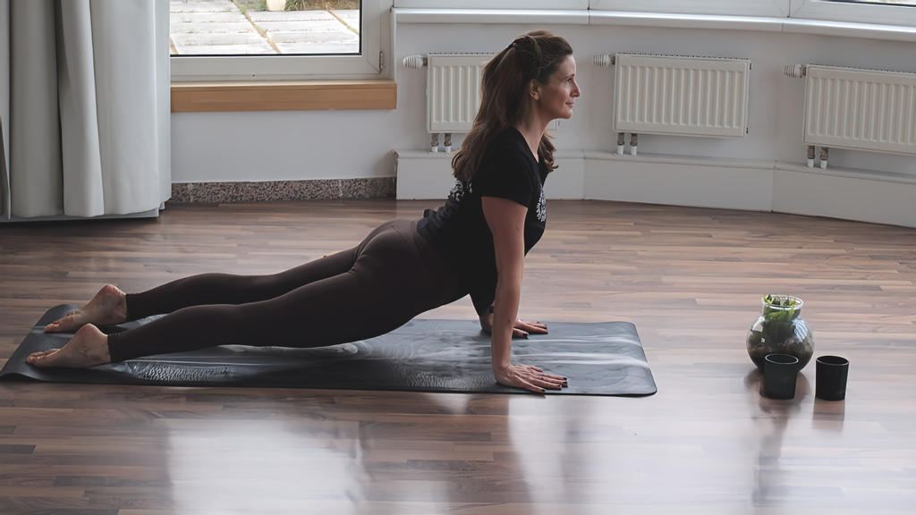 Frau in Trainingsgewand auf der Yoga-Matte beim Dehnen