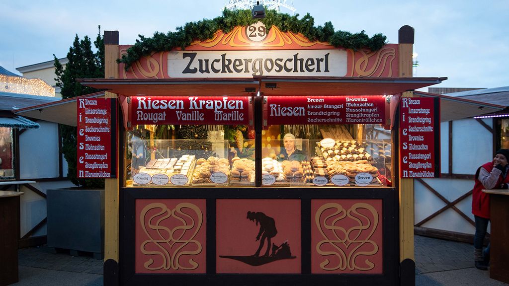 Weihnachtsmarkt-Stand mit Verkäuferin hinter dem Tresen.
