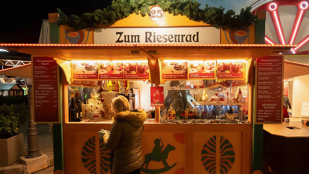 Eine Frau und eine Mitarbeiterin am Wintermarkt vor bzw. in einer Hütte