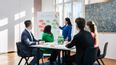 Gruppe an Personen sitzen in einem Seminarraum bei einem Brainstorming zusammen