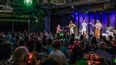 Eine Band spielt auf er Bühne vor Publikum an den Tischen