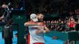 Zwei Sportler umarmen sich auf einem Indoor Tennis Court