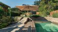 Schön gestalteter Garten mit Pool und aufgeklappten Sonnenschirm
