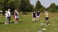 Eine Gruppe an Personen mit einem Golftrainer auf einem Golfplatz