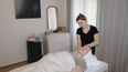 Frau liegt am Rücken und lässt sich den Nacken von der Masseurin massieren