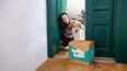 Frau mit Hund steht im Eingangsbereich ihrer Wohnung mit einem HelloBello Paket