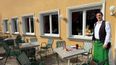 Ein Kellner steht mit einer Speise im Gastgarten 
