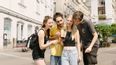 Gruppe von zwei Mädchen und zwei Burschen die mit einem Smartphone in der Hand Rätsel lösen