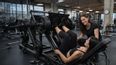 Personaltrainerin unterstützt Frau bei einer Beinpresse im Fitnesstudio