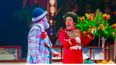 Ein Clown mit einem bunten Blumenstrauß steht einem anderem Clown in der Manege gegenüber und lacht