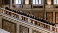 Chorensemble Chorus Viennensis in Anzügen auf einer prunkvollen Treppe in historischem Gebäude