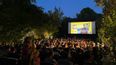 Im Park sitzendes Publikum vor einer beleuchteten Leinwand
