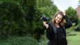 Fotografin mit Kamera in der Hand auf einer Wiese