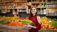 Frau steht im Naturkostladen vor vollen Regalen