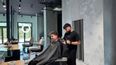 Ein Friseur schneidet einem Kunden in einem modernen, hellen Salon die Haare