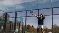 Ein Mann retourniert den Ball beim Padeltennisspielen im Freien