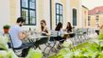 Eine Gruppe an Personen beim Essen im Schloss-Restaurant im Freien