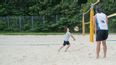 Kinder und ein Erwachsener beim Beachvolleyballfeld