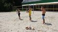 Mehrere Personen spielen Beachvolleyball auf einem Sandplatz