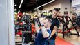 Personal Trainer unterstützt Mann bei einem Fitness Gerät im Fitness Studio
