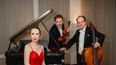 Drei Musiker*innen des Trio Appassionato vor einem Flügel mit Violine und Cello