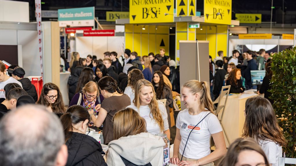 Viele Menschen in einer Halle bei einer Messe an einem Messestand
