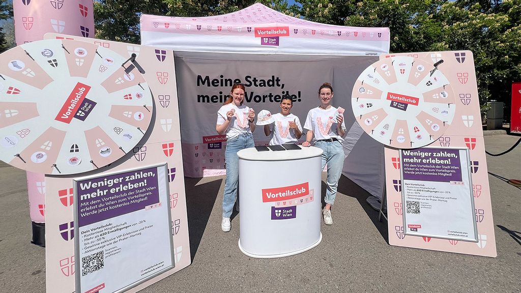 Drei Promotorinnen mit VC-Shirts  stehen vor dem Vorteilsclub Stand zwischen zwei Glücksrädern