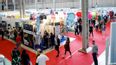 Menschen in einer Messehalle mit Ständen