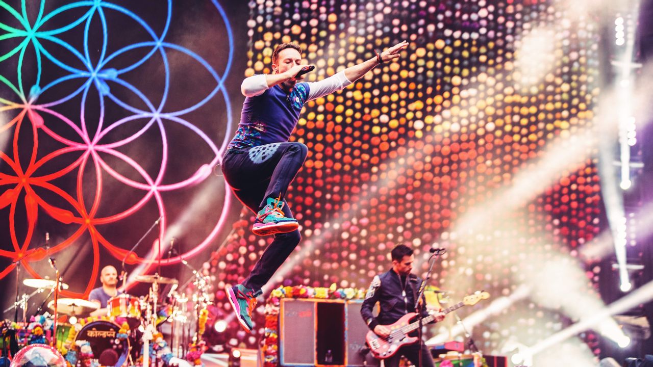 Coldplay Sänger Chris Martin auf der Bühne vor buntem Bühnenbild