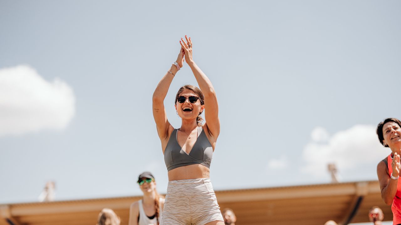 Eine Frau in Sportkleidung, die lächelnd Yoga macht
