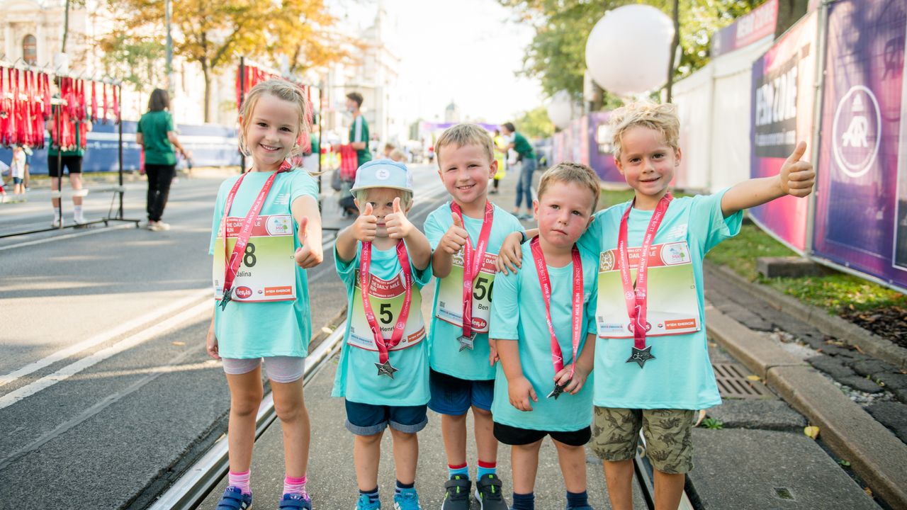Fünf Kinder in Sportklamotten mit Startnummern und Medaillen 