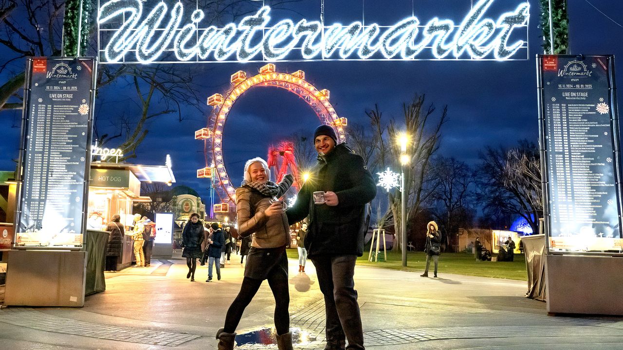 Ein Pärchen steht vor dem beleuchteten Eingang zum Wintermarkt am Riesenradplatz im Prater