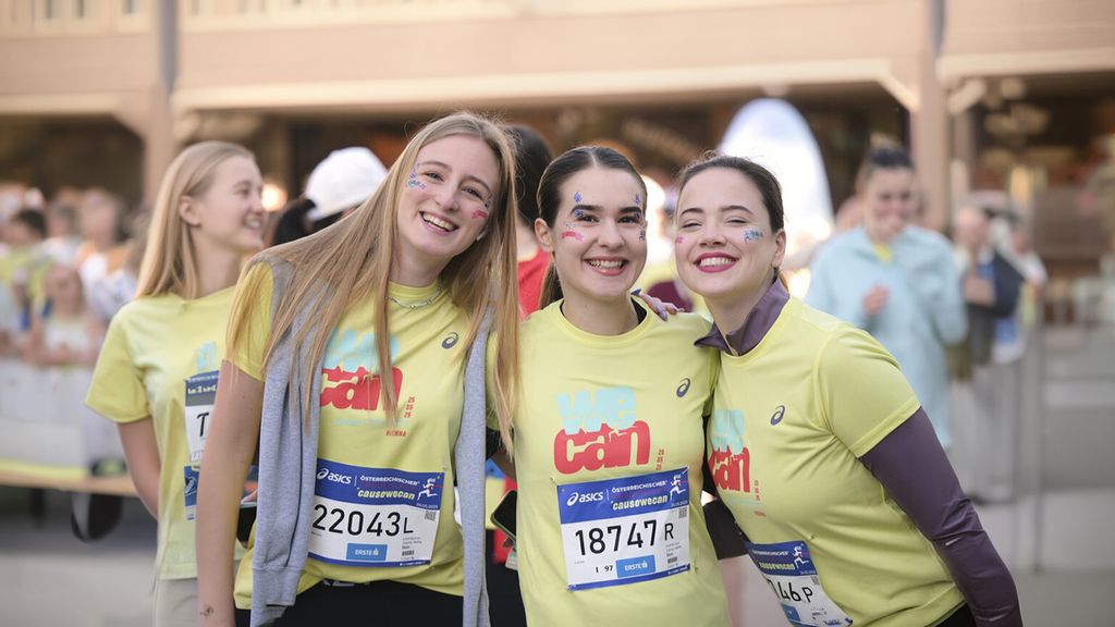 Drei Frauen in einem Laufshirt mit Starnummern darauf lachen in die Kamera