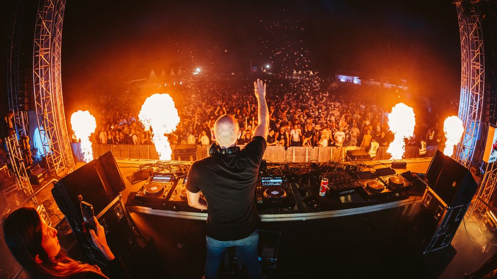DJ auf der Bühne mit Feuer vor sich und Publikum