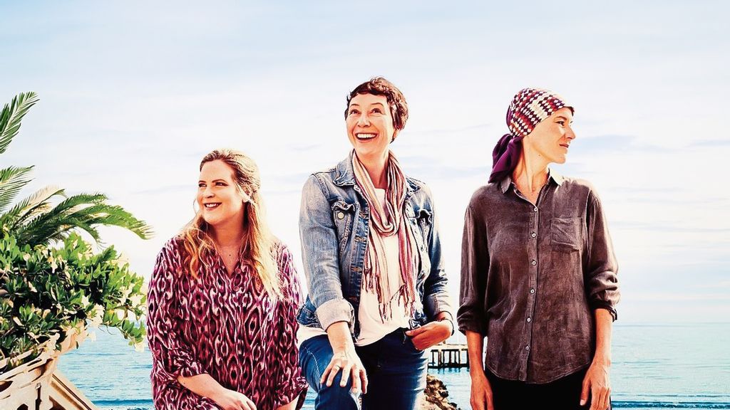 Drei Frauen stehen nebeneinander und lächeln