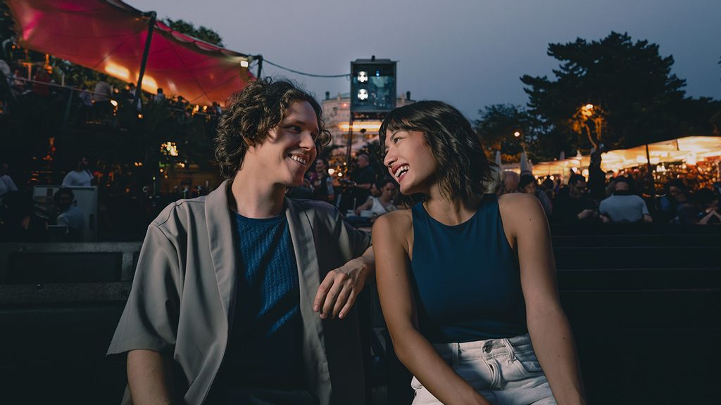 © Flo Mitteregger Zwei Personen sitzen am Abend auf einer Bank und lachen sich an
