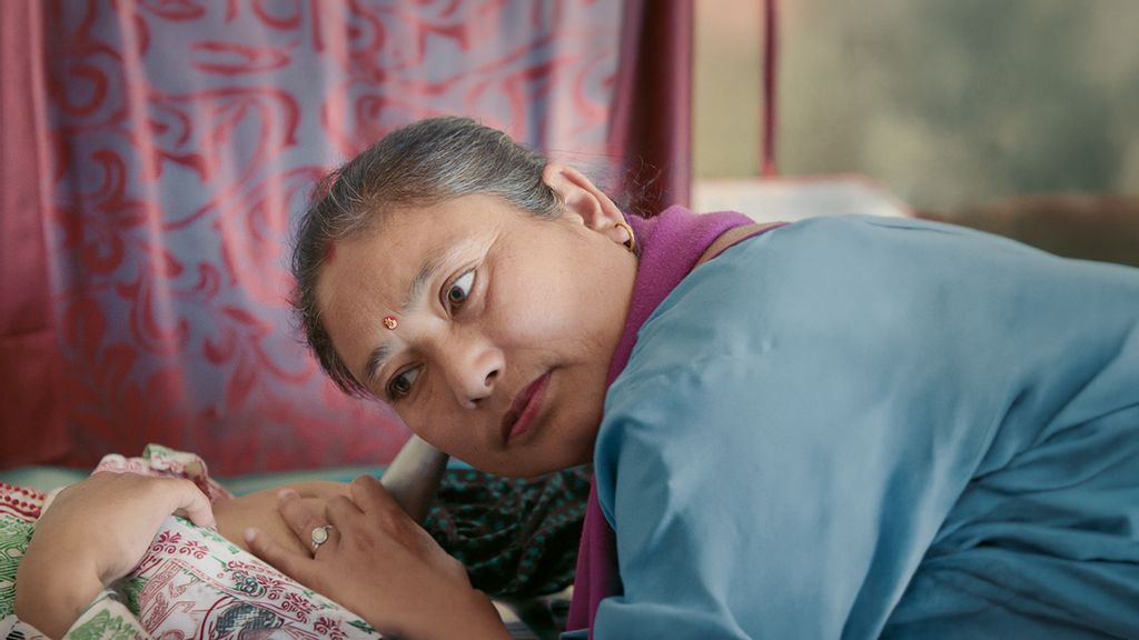 Eine indische Frau hält ihren Kopf gebeugt und hört an einem Bauch