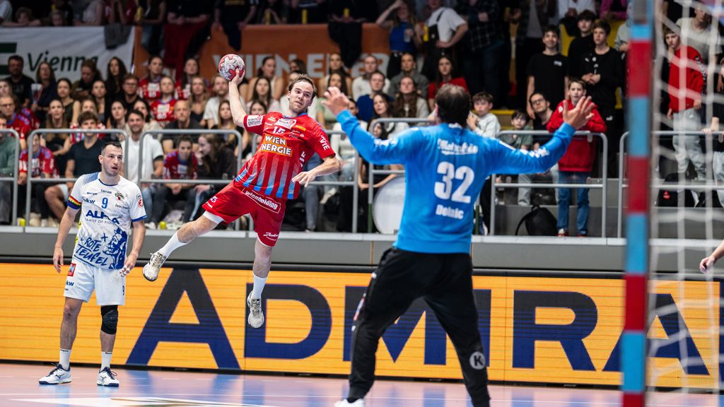 Ein Handballer springt in der Luft mit einem Handball in der Hand