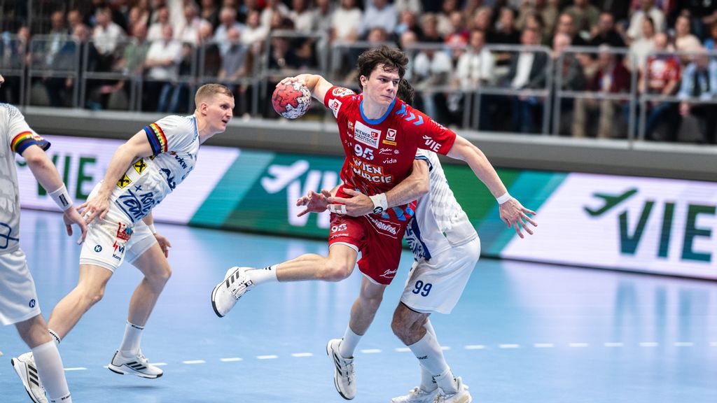 Ein Handballer springt in der Luft mit einem Handball in der Hand