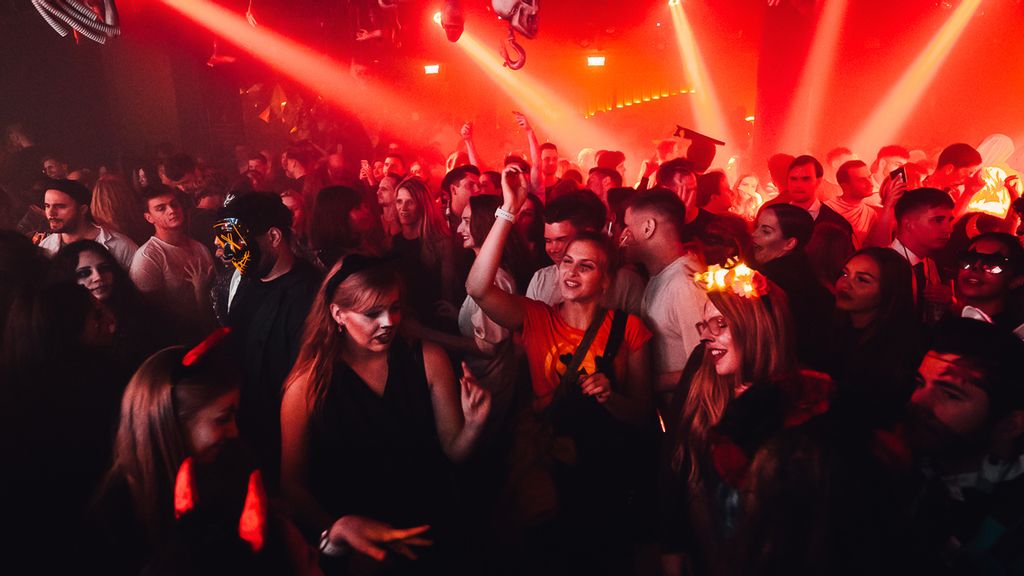 Verkleidete Partygäste tanzen bei roter Lasershow
