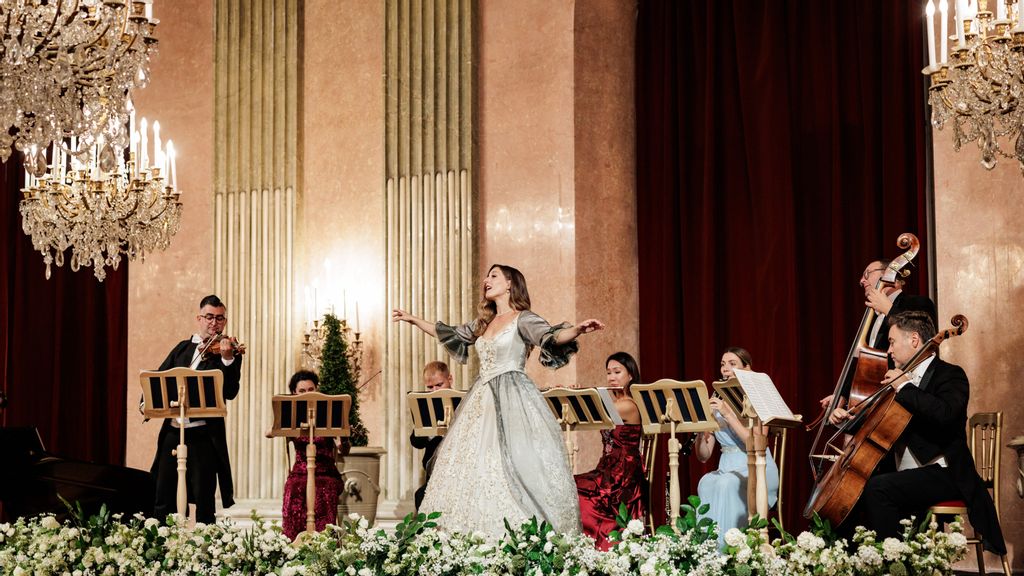 Eine Sängerin in einem barocken Kleid auf einer mit Blumen geschmückten Bühne