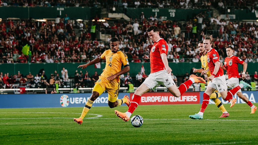 Fußballer am Spielfeld und einer schießt mit dem Fuß auf den Ball
