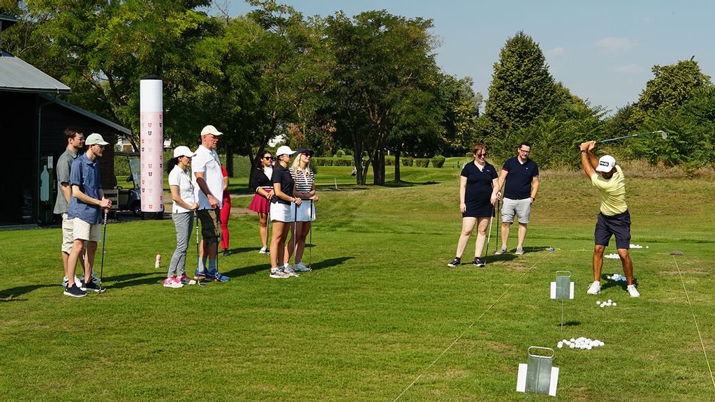 Personen am Golfplatz mit Ball und Schläger