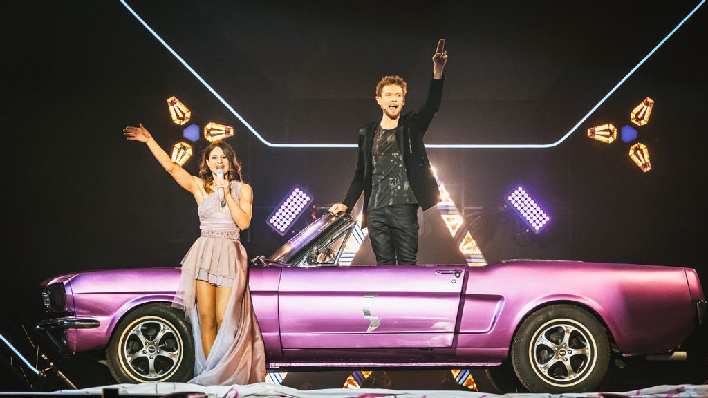 Thommy Ten und Amélie van Tass auf der Bühne mit einem rosa farbigen Oldtimer