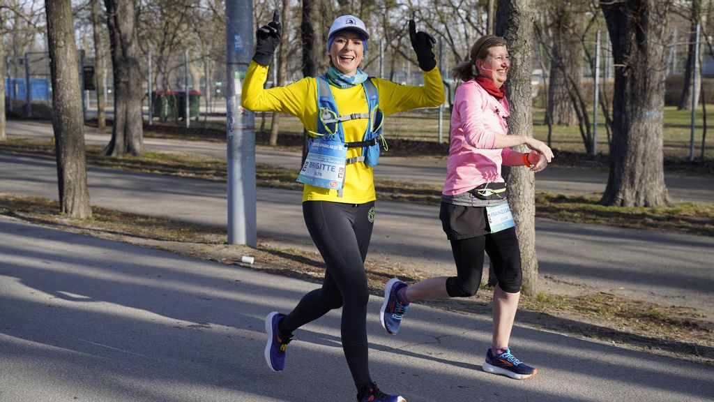 Zwei Frauen laufen in der Prater Hauptallee entlang. Eine der beiden hält die Hände in die Höhe. 